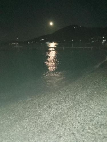 a moon over a body of water at night at Villa Angela, Traditional Villa in the village in Agios Ioannis Peristeron