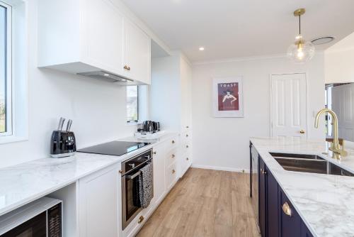 a kitchen with white cabinets and a counter top at Three on Wilson in Martinborough 