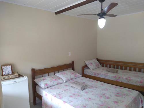a bedroom with two beds and a ceiling fan at Pousada Marimbá in Trindade