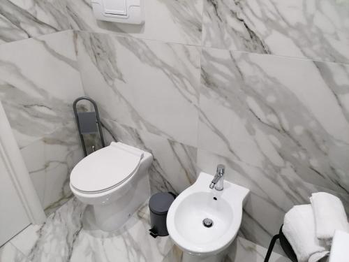 uma casa de banho com um WC branco e um lavatório. em [Centro Storico] Casa Elegante per Famiglia em Nápoles