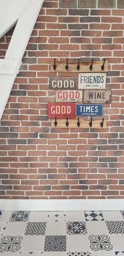 a brick wall with signs that saygood friends good wine and good times at Gîte Lucian Mont-saint-michel in Moidrey