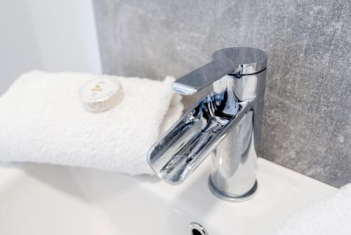 a bathroom sink with a faucet and a roll of toilet paper at Wrexham Central Stay Apartment Seven in Wrexham