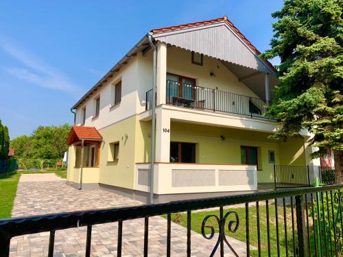 uma casa amarela e branca com uma cerca preta em Pine&Chill2 Apartments em Balatonalmádi