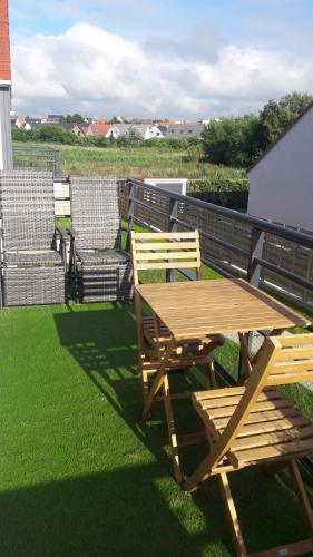 ein Picknicktisch aus Holz und Stühle auf dem Gras in der Unterkunft Studio Cosy neuf proximité du Golf et de la Digue in Wimereux