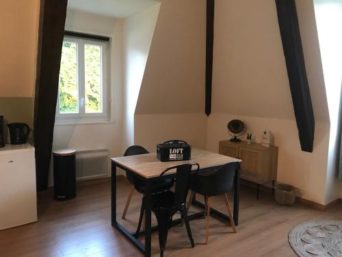 a table and chairs in a room with a window at El Castillo, aux portes de Honfleur in Gonneville-sur-Honfleur