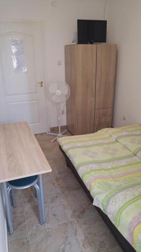 a bedroom with a bed and a table and a cabinet at Vasti Apartman in Siófok