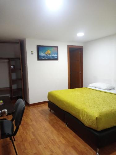 Un dormitorio con una cama, una mesa y una silla. en Embassy On Holidays, en Bogotá