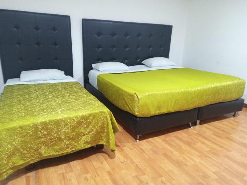 two beds with green sheets in a room at Embassy On Holidays in Bogotá