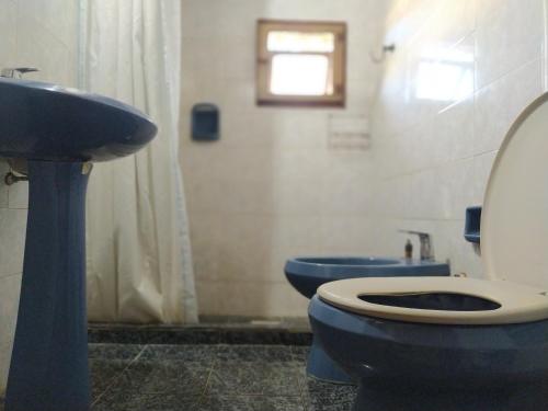 uma casa de banho com um WC azul e um lavatório. em Casa cómoda en Barra del Chuy, Uruguay em Barra del Chuy