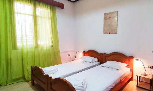 a bedroom with two beds and a green curtain at Fouli Studios & Apartments in Rethymno Town