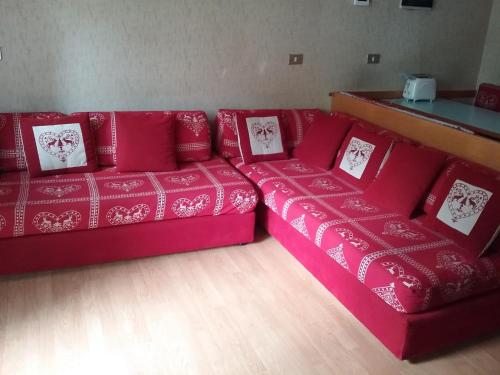 um sofá vermelho com almofadas num quarto em Appartamento a CERVINIA - CIELOALTO em Breuil-Cervinia