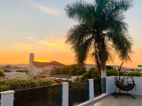 a palm tree on the roof of a house with the sunset at Pousada Cambará Suítes in Bonito
