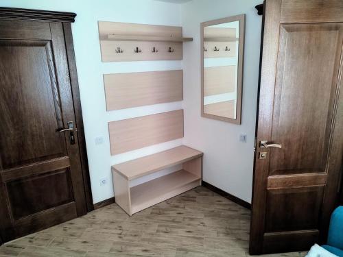 a closet with wooden doors and shelves and a mirror at Готель-ресторан "Олеся" in Berehove