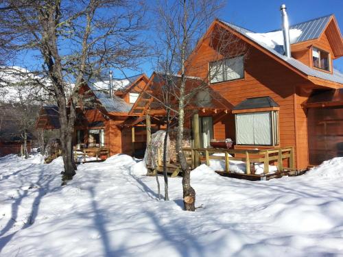 a wooden house with snow on the ground at Cabañas Maroni in Las Trancas