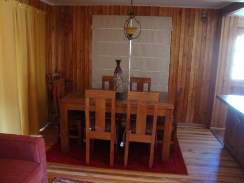 una mesa de comedor y sillas con un jarrón encima en Cabañas Maroni, en Las Trancas