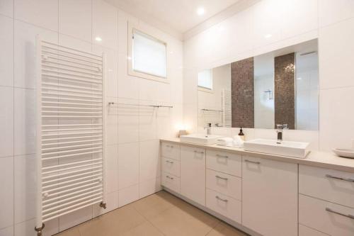 a white bathroom with two sinks and two mirrors at Blair Street - Luxury Home with Pool and Theatre in Moama