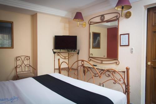 een slaapkamer met een bed, een spiegel en een televisie bij Hotel Santa Maria in Mexico-Stad