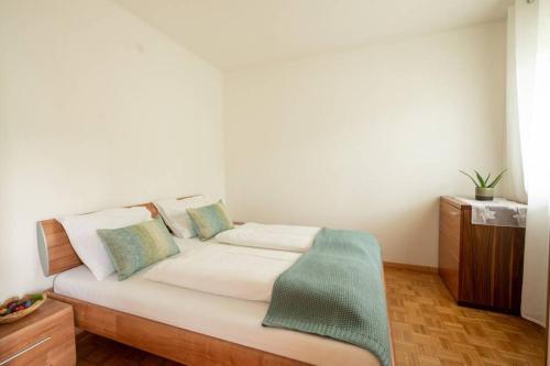 ein weißes Bett mit einer grünen Decke darüber in der Unterkunft Ferienwohnung am Kalterer See in Südtirol in Kaltern