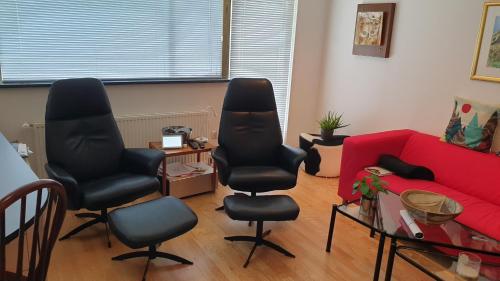 a living room with two chairs and a red couch at Vanny's Guesthouse in Ytri-Njarðvík