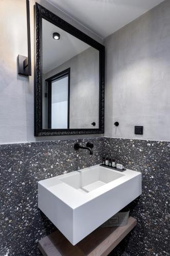 a bathroom with a white sink and a mirror at The Athenians Art Apartments in Athens