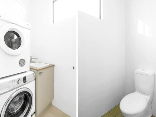 a bathroom with a washing machine and a toilet at Neptune Hyams Beach in Hyams Beach