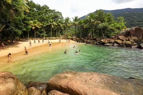 un grupo de personas jugando en el agua en una playa en Efferus Hostel, en Ubatuba
