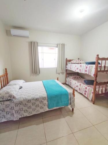 a bedroom with three beds and a window at Pousada Origin in Guarda do Embaú