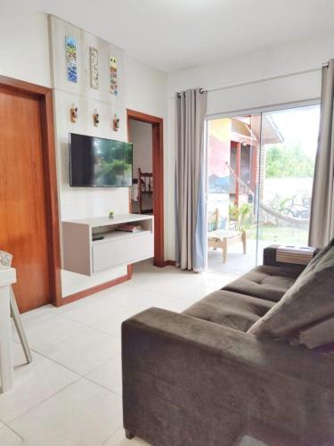 a living room with a couch and a flat screen tv at Pousada Origin in Guarda do Embaú