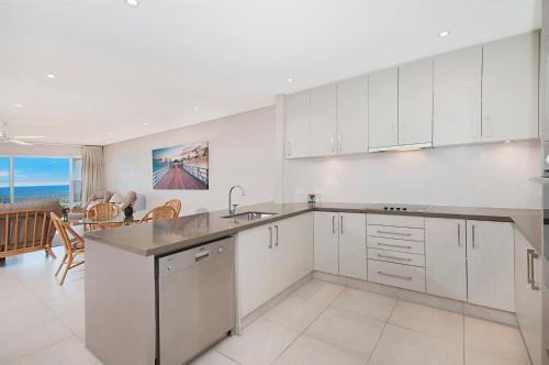a kitchen with white cabinets and a view of the ocean at Quarterdeck 20 in Lennox Head