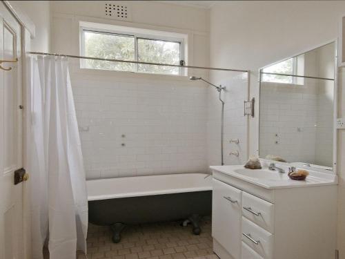 a bathroom with a bath tub and a sink at Hollyoak Cottage in Bowral