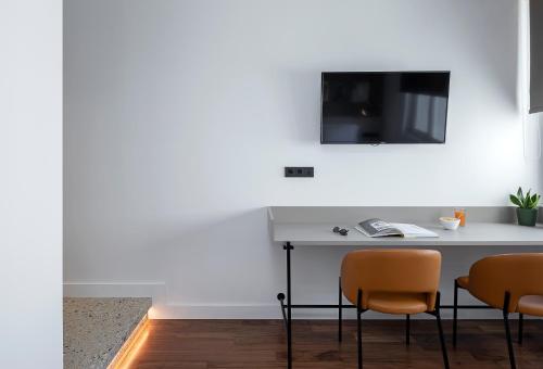 a table with two chairs and a television on a wall at The Athenians Art Apartments in Athens