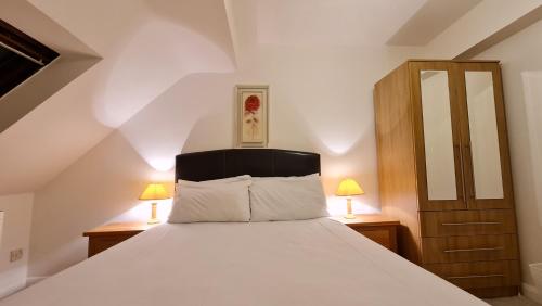 um quarto com uma cama branca e 2 candeeiros em Grace Apartments - Living Stream 1 em Ashford