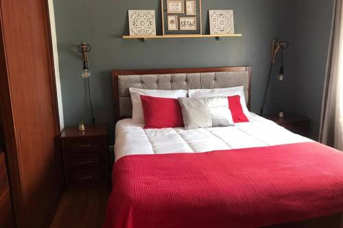 a bed with red and white sheets and pillows at #GC House in Ponta Delgada