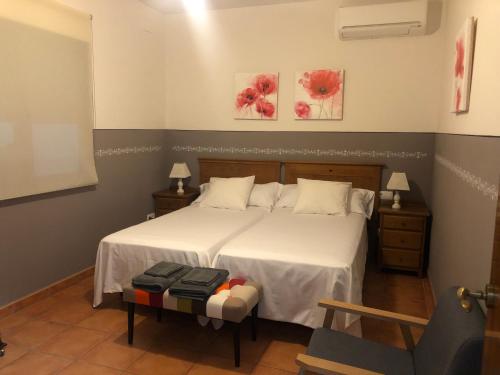 een slaapkamer met een bed met witte lakens en bloemen aan de muur bij Casa Rural La Candelaria in Burujón