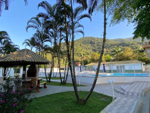 einen Pool mit Palmen und einem Pavillon in der Unterkunft AP COM PISCINA, CHURRASQUEIRAS, AR CONDICIONADO, até 08 adultos in Ubatuba