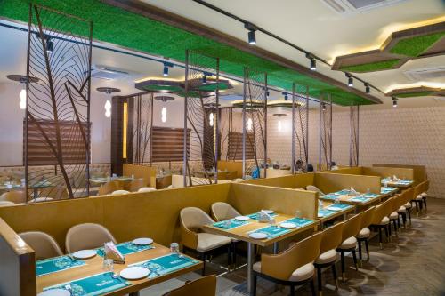 un ristorante con tavoli, sedie e pareti verdi di Viceroy Residency Manor a Rāmanathapuram
