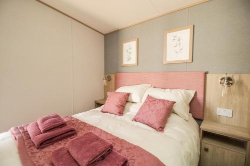 a bedroom with a large bed with pink pillows at Burlees Nest in Cockermouth