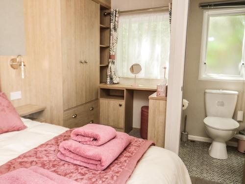 a bedroom with a bed with pink towels on it at Burlees Nest in Cockermouth