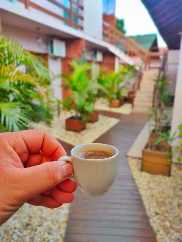 a person is holding a cup of coffee at Pousada Origin in Guarda do Embaú