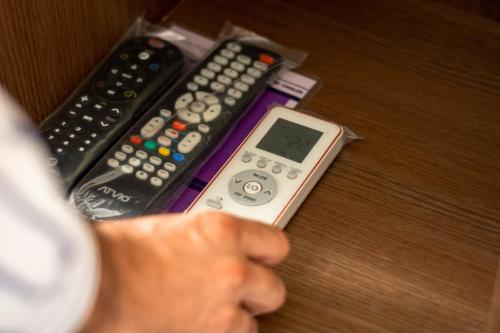 a person holding a remote control next to three remote controls at Hotel San Miguel, en el Centro - Desayuno Incluido in Tuxtla Gutiérrez