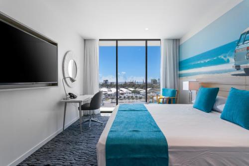 a hotel room with a large bed and a flat screen tv at Rydges Gold Coast Airport in Gold Coast