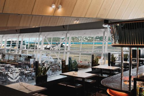a restaurant with tables and chairs and a large window at Rydges Wellington Airport in Wellington