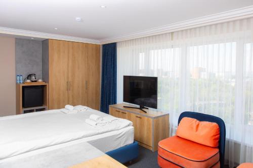 a hotel room with a bed and a tv and a chair at Отель KOKSHETAU in Kokshetau