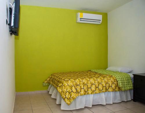 1 dormitorio con 1 cama con pared verde en Hotel Bugambilias, en Ciudad Obregón