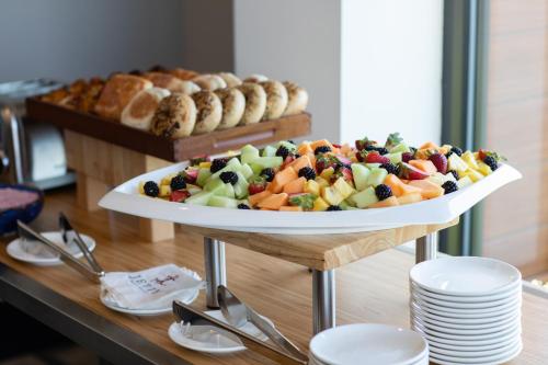 a tray of fruit salad on a table with plates at Hotel Indigo Seattle Everett Waterfront Place by IHG in Everett