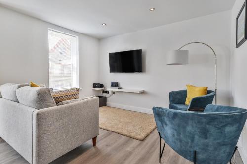a living room with two chairs and a tv at Finest Retreats - Belle House, Apt 4 in Filey