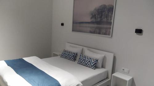 a bed in a white room with a picture on the wall at SB River Hotels in Atyraū