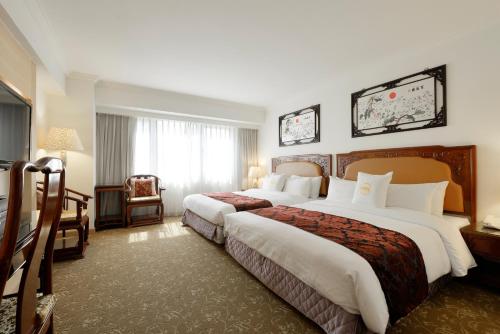 a hotel room with two beds and a window at Hotel Sunshine in Kaohsiung