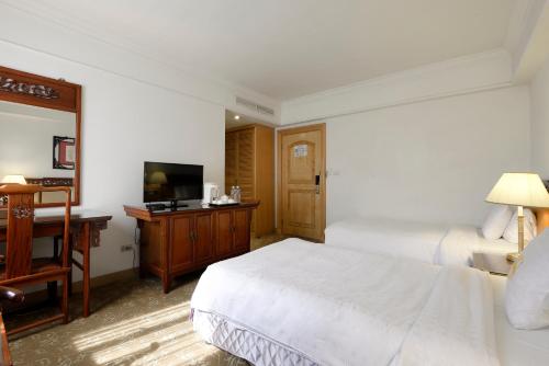 a hotel room with two beds and a flat screen tv at Hotel Sunshine in Kaohsiung