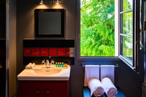 a bathroom with a sink and a window and towels at Hôtel Villa la Renaissance in Bayonne